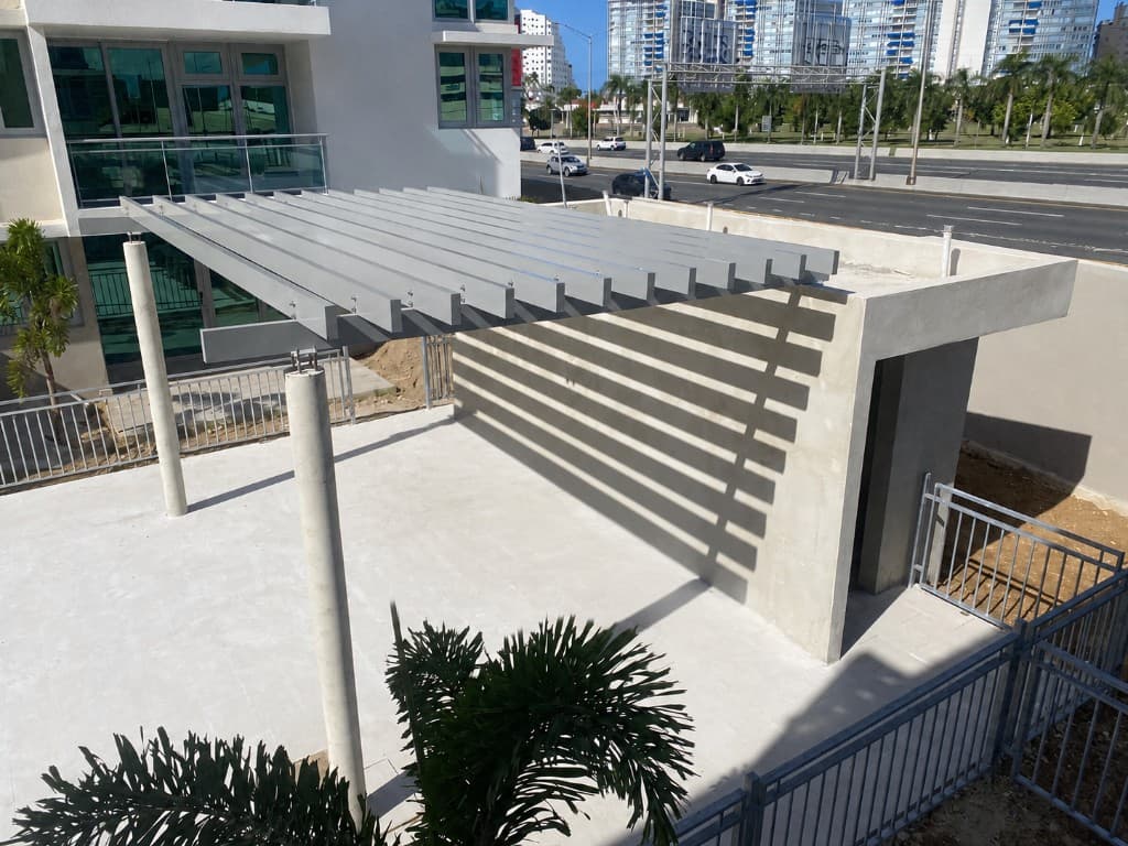 Slatted metal shade pergola over terrace with railings